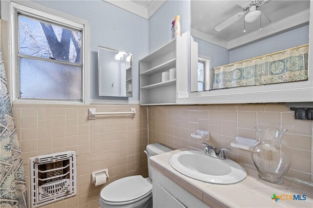 bathroom with vanity, crown molding, toilet, tile walls, and heating unit