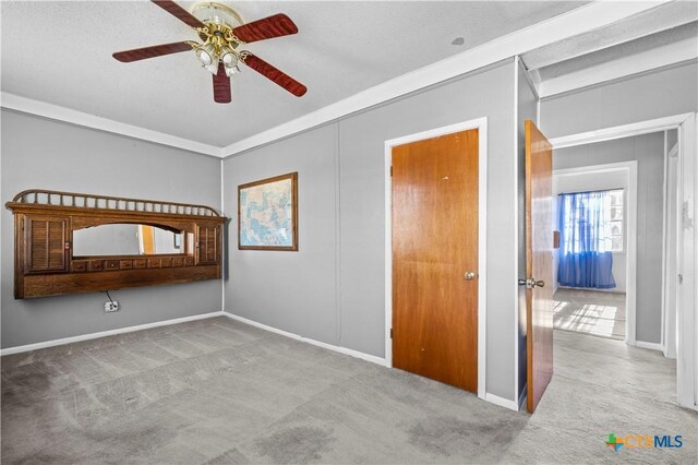 unfurnished bedroom featuring ceiling fan, light colored carpet, and ornamental molding