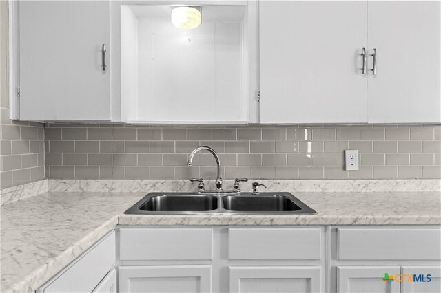 kitchen featuring backsplash, white cabinets, and sink