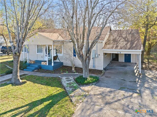 view of front of house featuring covered porch, a carport, and a front lawn