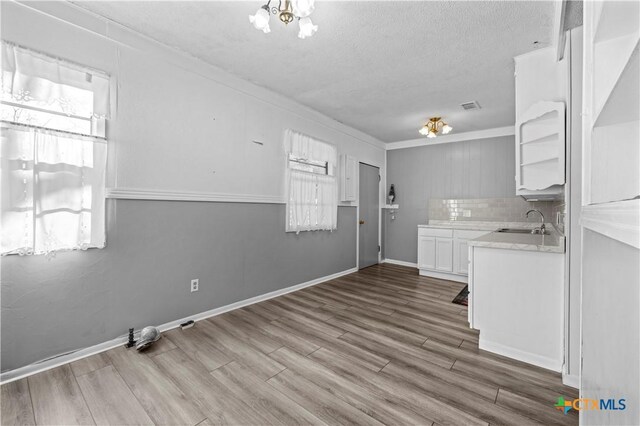 kitchen featuring decorative backsplash, a textured ceiling, sink, wood-type flooring, and white cabinetry