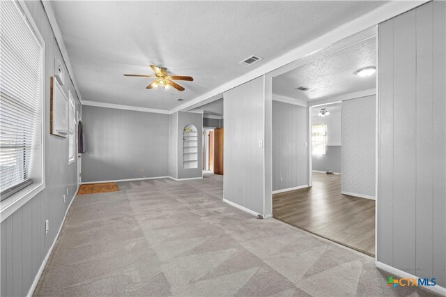 carpeted spare room featuring a textured ceiling, ceiling fan, and ornamental molding