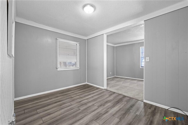 spare room with plenty of natural light, ornamental molding, and a textured ceiling