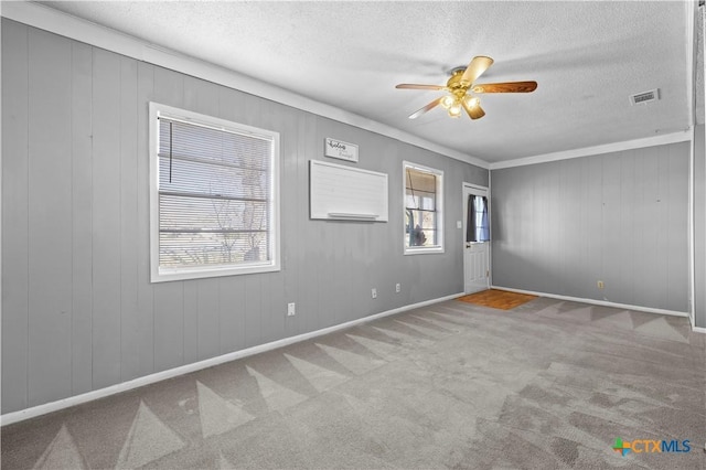 unfurnished room with ceiling fan, light colored carpet, plenty of natural light, and crown molding