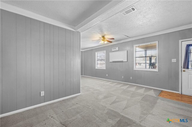 interior space featuring light colored carpet, ceiling fan, and wooden walls