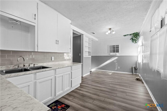 kitchen with backsplash, a textured ceiling, sink, hardwood / wood-style flooring, and white cabinets