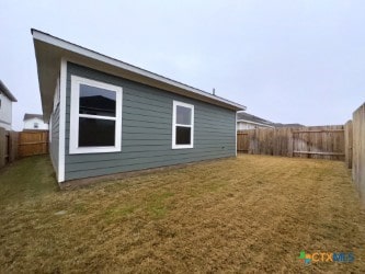 back of house with a lawn and a fenced backyard