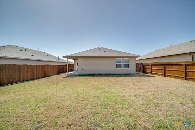 back of property with a lawn and a fenced backyard