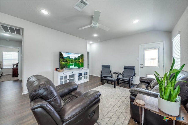 living area with visible vents, vaulted ceiling, and wood finished floors