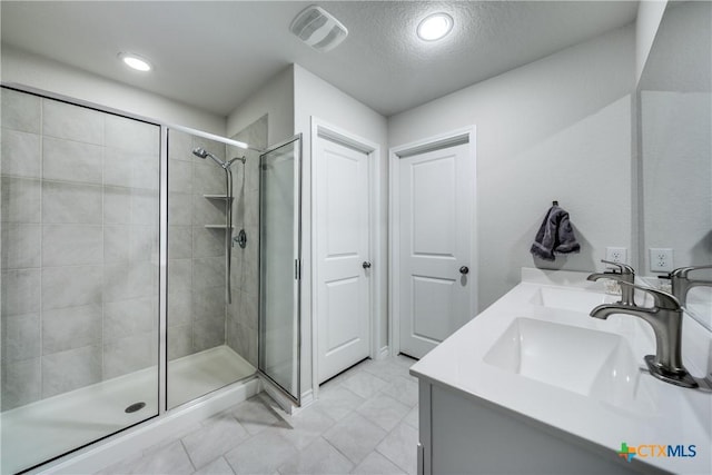 bathroom featuring a stall shower, a sink, and visible vents