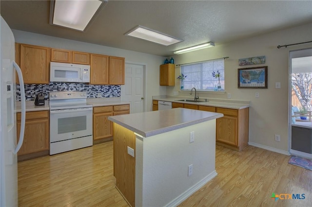 kitchen featuring white appliances, sink, a kitchen island, and light wood-type flooring