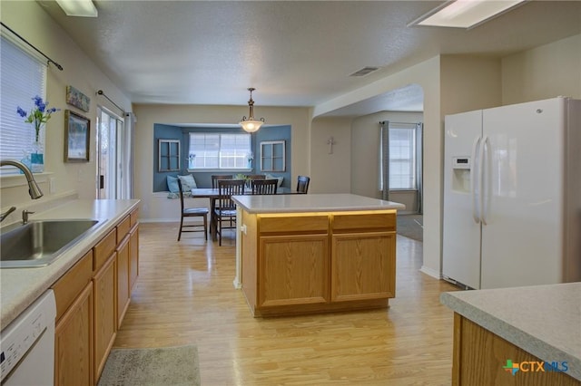 kitchen featuring sink, a center island, pendant lighting, white appliances, and light hardwood / wood-style floors