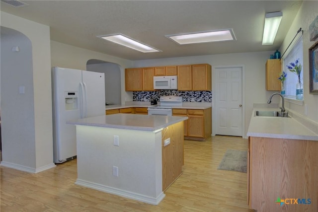 kitchen featuring sink, white appliances, a center island, and light wood-type flooring