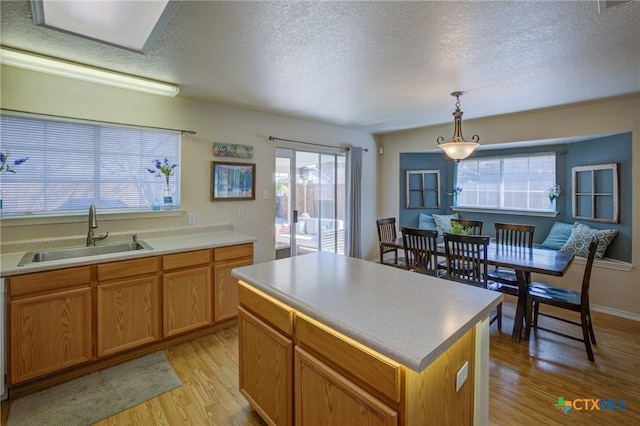 kitchen with pendant lighting, sink, a center island, a wealth of natural light, and light wood-type flooring