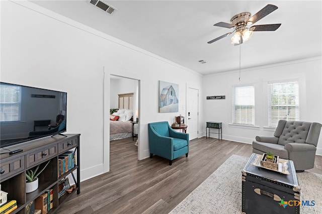 living room featuring hardwood / wood-style floors, ceiling fan, and crown molding