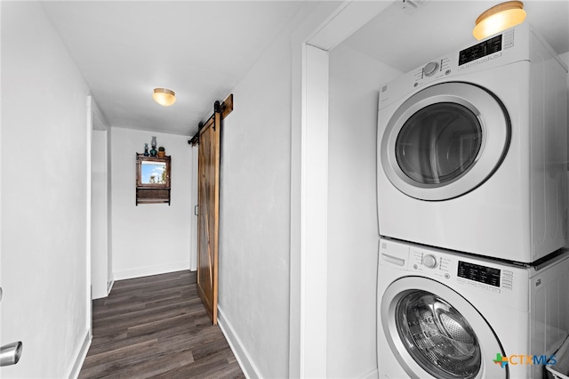 laundry room featuring a barn door, dark wood-type flooring, and stacked washer / drying machine