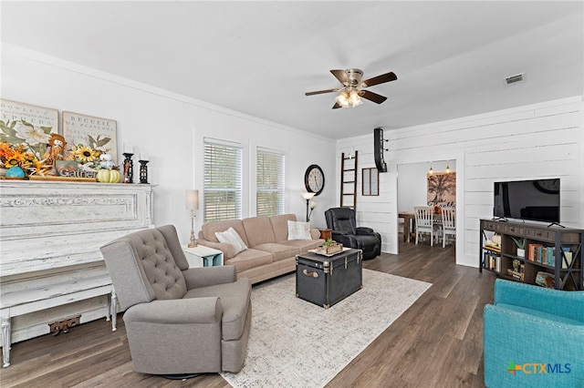 living room featuring dark wood-type flooring, ceiling fan, and crown molding