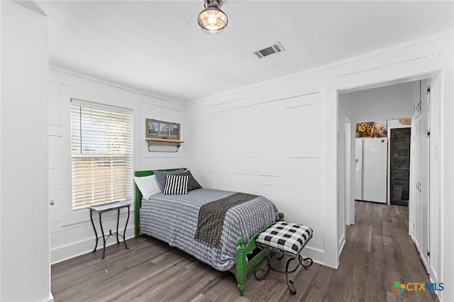 bedroom with dark wood-type flooring and white fridge with ice dispenser