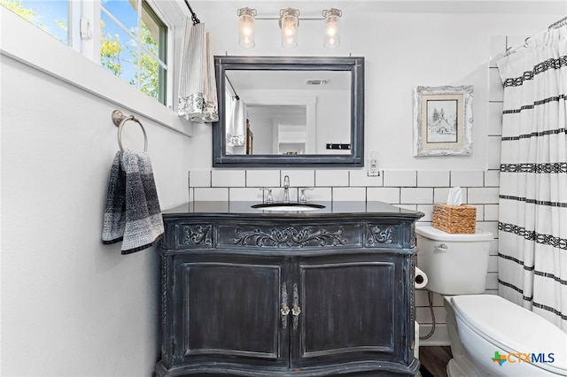 bathroom featuring toilet, vanity, and tile walls