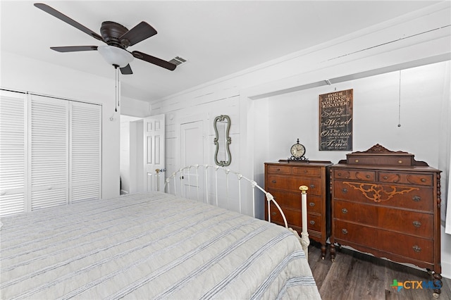 bedroom with dark wood-type flooring, ceiling fan, wooden walls, and a closet