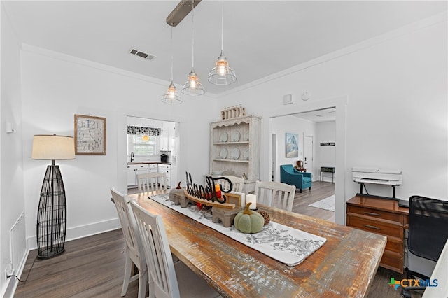 dining room with dark wood-type flooring and crown molding