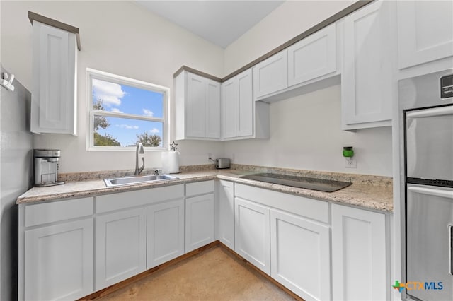 kitchen with black electric cooktop, white cabinetry, sink, and double oven