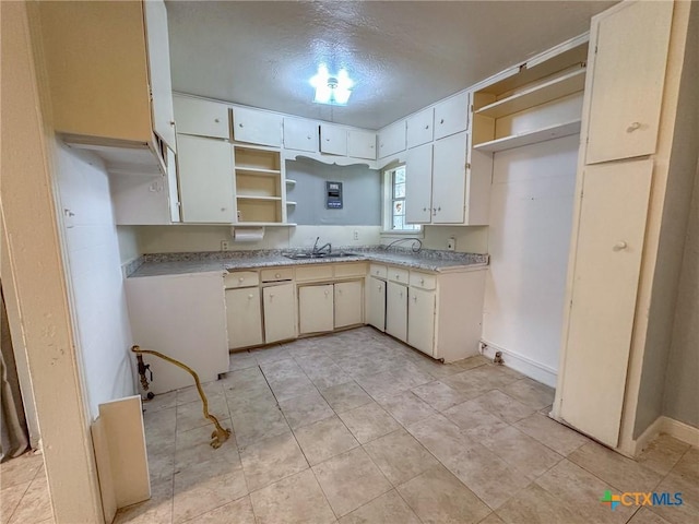 kitchen featuring white cabinets, a textured ceiling, and sink