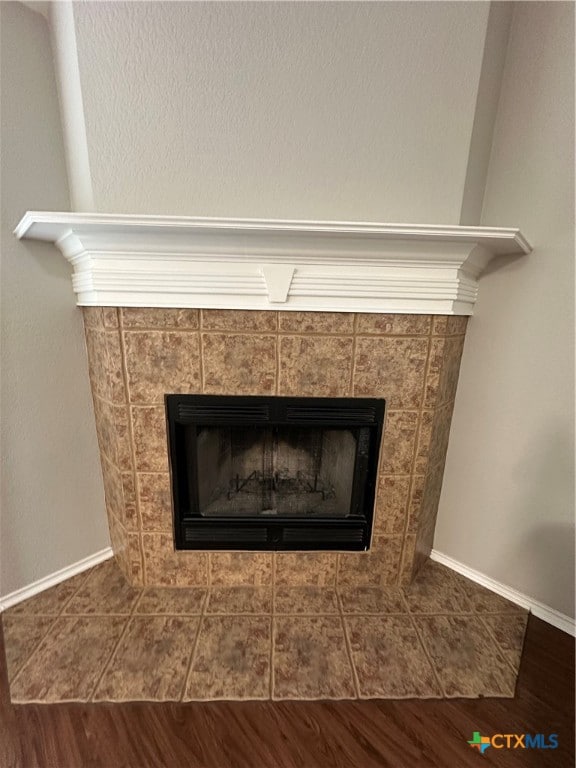 interior details featuring hardwood / wood-style floors and a tile fireplace