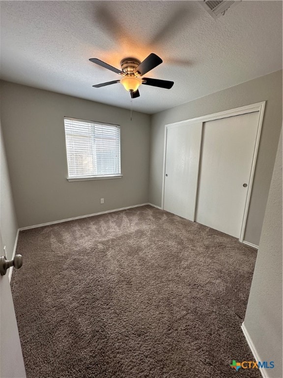 unfurnished bedroom featuring a closet, a textured ceiling, carpet flooring, and ceiling fan