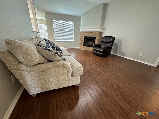 living room featuring a tiled fireplace and dark hardwood / wood-style floors