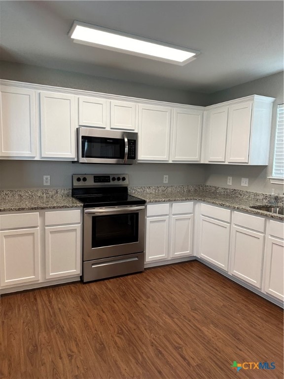 kitchen featuring white cabinetry, light stone counters, dark hardwood / wood-style floors, and stainless steel appliances