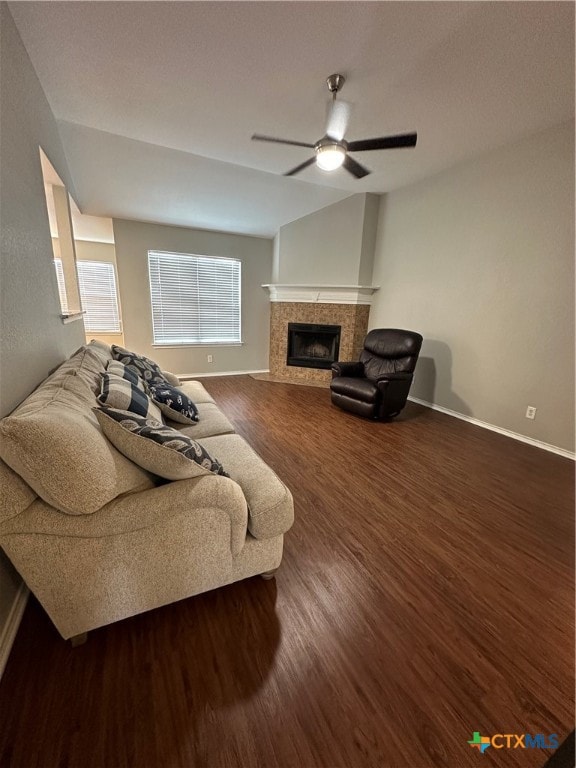 living room featuring dark wood-type flooring, vaulted ceiling, a fireplace, and ceiling fan