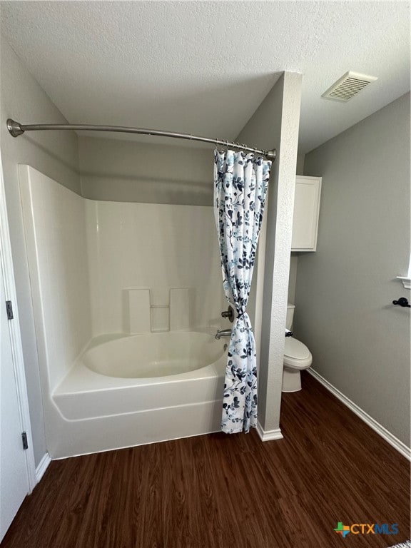 bathroom with hardwood / wood-style floors, a textured ceiling, toilet, and shower / tub combo