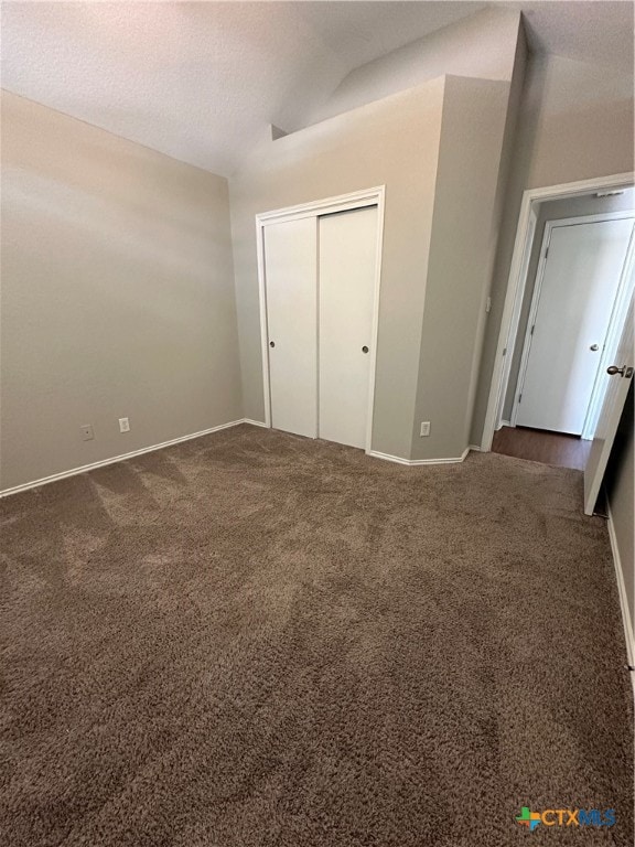 unfurnished bedroom with a closet, a textured ceiling, and dark colored carpet