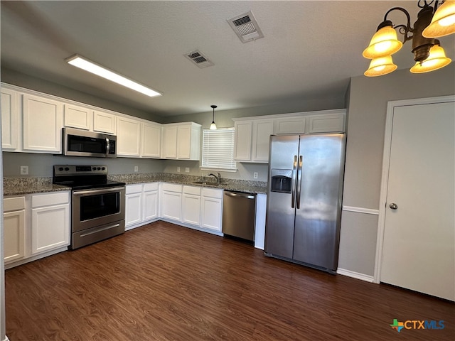 kitchen with white cabinets, dark wood-type flooring, appliances with stainless steel finishes, and hanging light fixtures