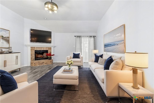 living room with lofted ceiling, a brick fireplace, wood finished floors, and baseboards