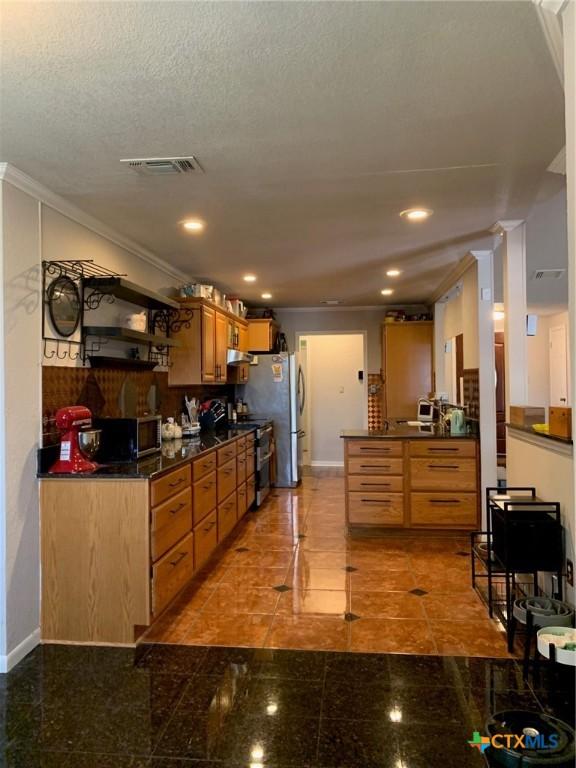 3002 Veterans Ave, Copperas Cove, TX 76522 - kitchen with dark countertops, stainless steel appliances, ornamental molding, brown cabinets, and recessed lighting
