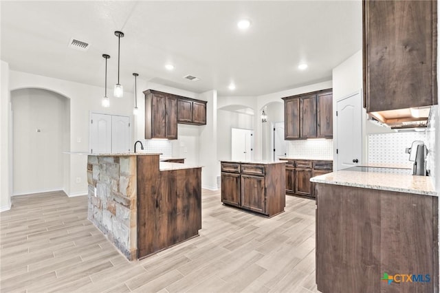 kitchen featuring a center island, pendant lighting, dark brown cabinets, and light hardwood / wood-style floors