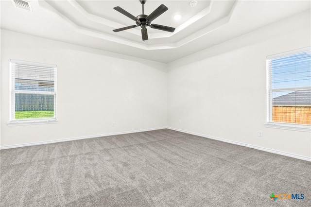 carpeted spare room featuring ceiling fan and a raised ceiling