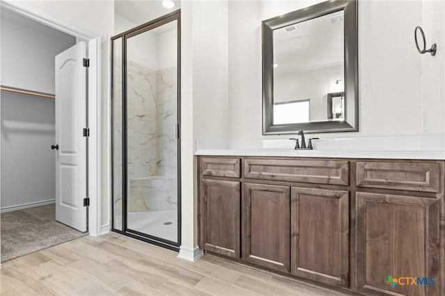 bathroom with hardwood / wood-style floors, vanity, and a shower with door