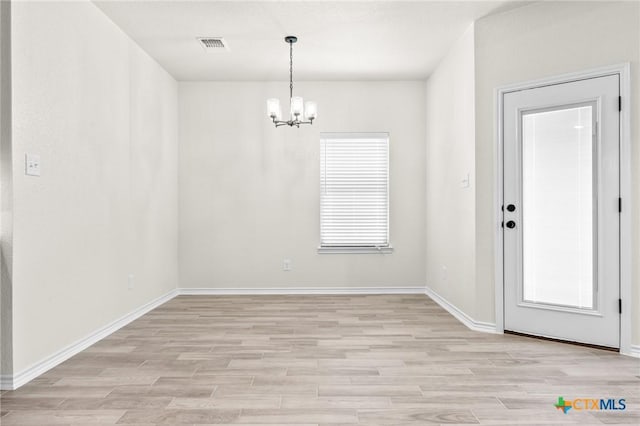 unfurnished dining area featuring a chandelier and light hardwood / wood-style floors