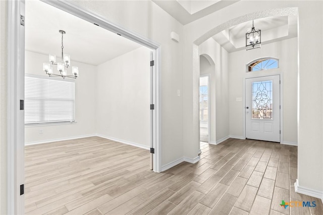 foyer featuring a tray ceiling, light hardwood / wood-style flooring, and a chandelier