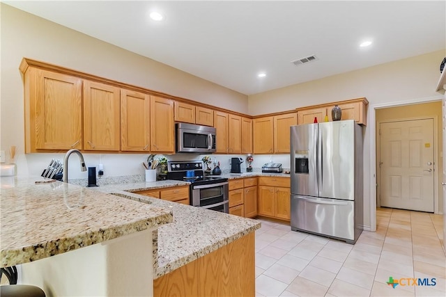 1518 Skyline Dr, Kingsland, TX 78639 - kitchen featuring appliances with stainless steel finishes, a peninsula, light stone counters, light tile patterned floors, and recessed lighting