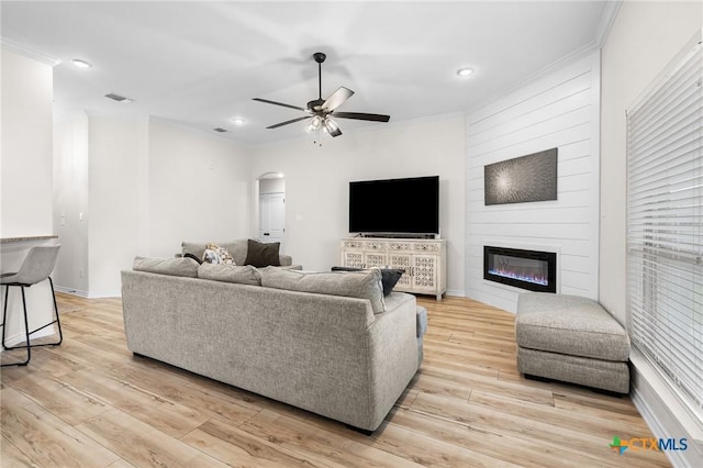 705 Juniper Dr, Troy, TX 76579 - living area with arched walkways, a ceiling fan, crown molding, light wood finished floors, and a large fireplace