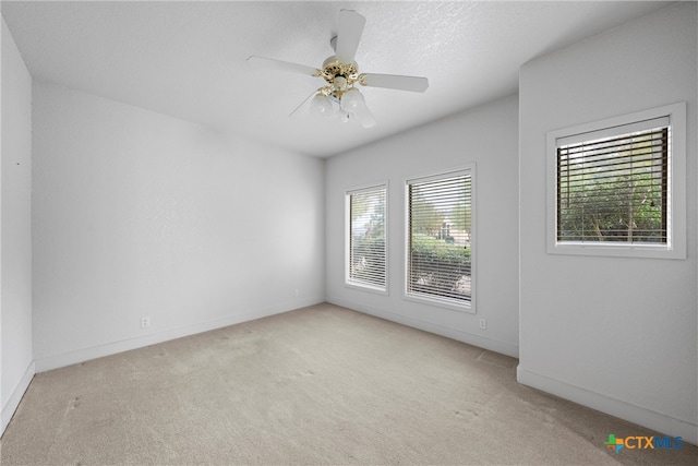 carpeted spare room with a textured ceiling and ceiling fan