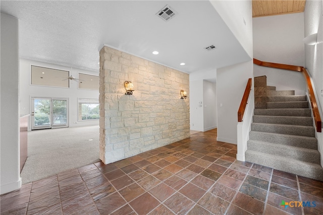 interior space with a towering ceiling, ceiling fan, a textured ceiling, and carpet floors