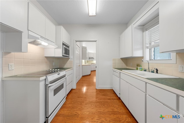 kitchen with white cabinetry, stainless steel microwave, sink, and light hardwood / wood-style floors