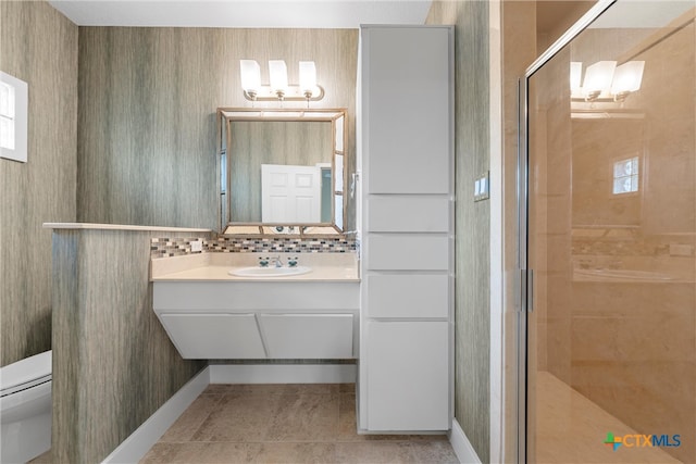 bathroom featuring toilet, tile patterned floors, a shower with door, vanity, and backsplash