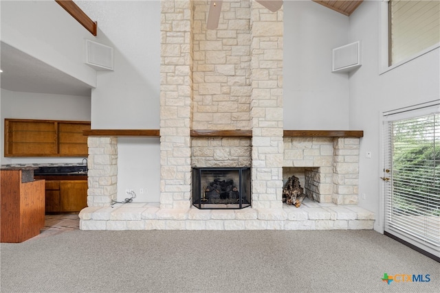 unfurnished living room with a fireplace, light carpet, high vaulted ceiling, and sink