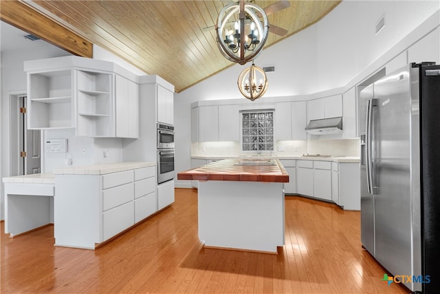 kitchen with tile counters, decorative light fixtures, appliances with stainless steel finishes, and a center island